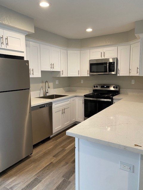 A kitchen with white cabinets and a stainless steel refrigerator.